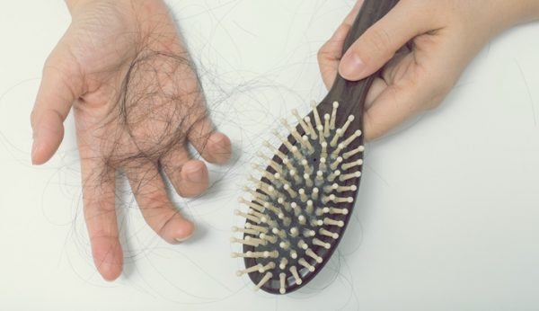 Hair loss in woman hands and bruch, on white background, women postpartum defluvium