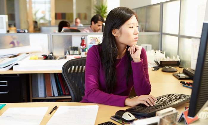 Asian Woman Working At Computer In Modern Office In Smart/Casual Dresswear