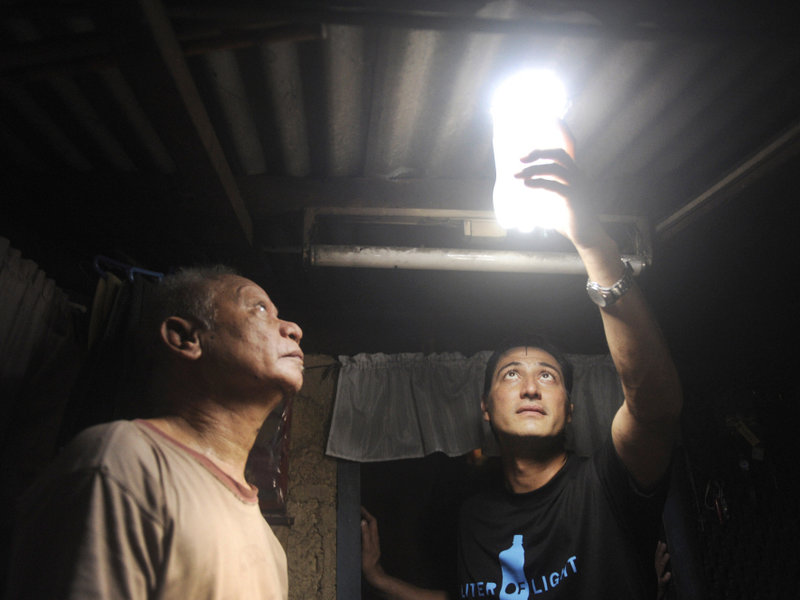 Illac Diaz inspects a solar light bulb with Siplicio Mondas, 73, in Manila. Diaz heads the nonprofit MyShelter Foundation, which is overseeing this solar lighting project.