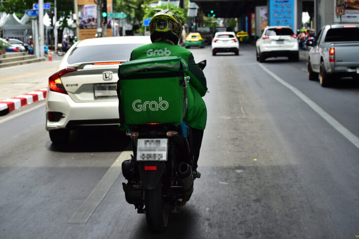 This photo taken on May 4, 2020 shows Grab Food delivery driver Yuttaphume Charnkanhaeng navigating traffic in Bangkok, as the volume of online food orders have soared since the stay home restrictions were put in place to fight the COVID-19 coronavirus. - Gourmet take-out delivered by a butler in a black sedan -- Thailand's super-rich have not forgone luxury during a pandemic which has locked the country down, crushed the economy and left millions unemployed. (Photo by Lillian SUWANRUMPHA / AFP) / TO GO WITH Health-virus-Thailand-social,FOCUS by Dene-Hern Chen